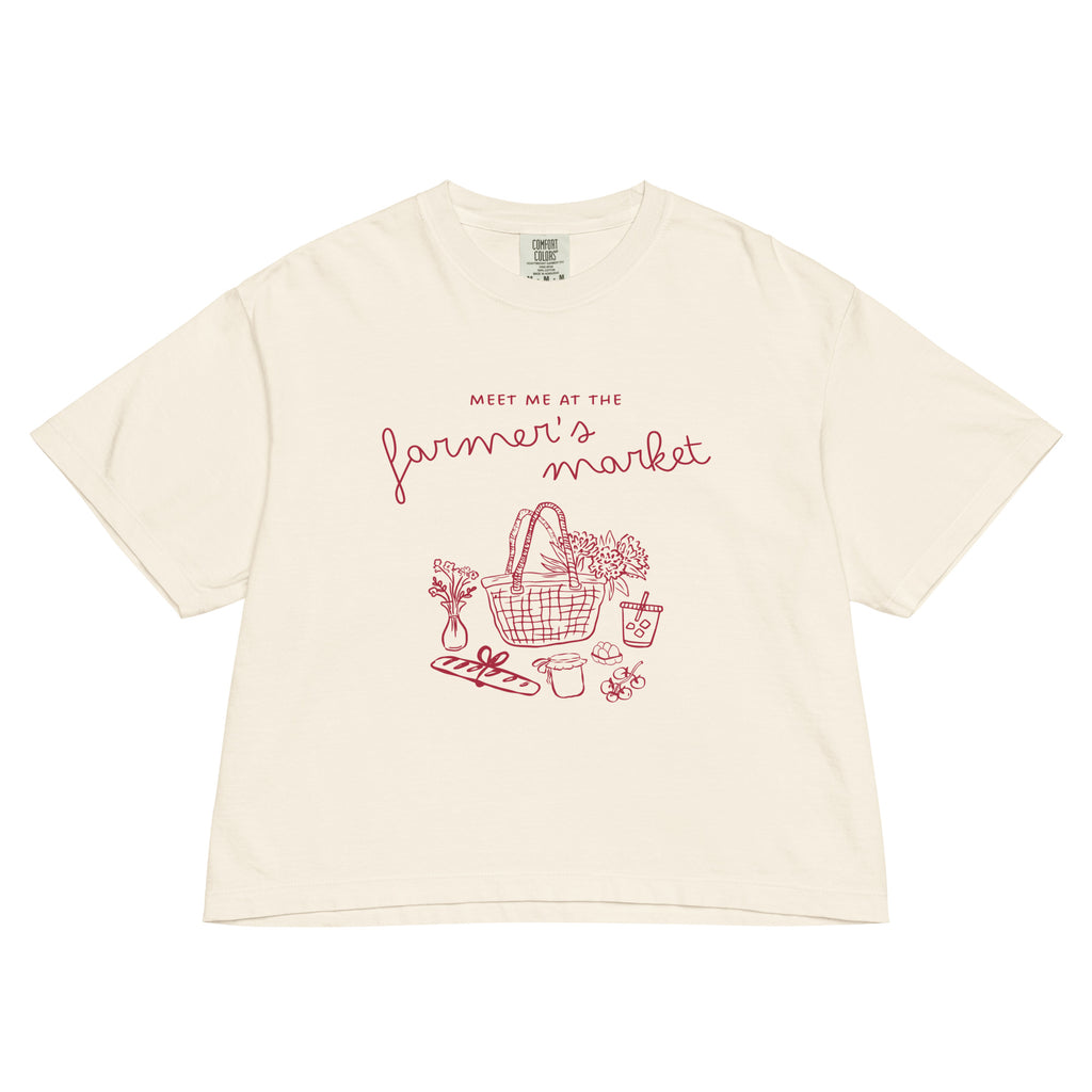 Beige t-shirt with red graphic and text 'meet me at the farmer's market' on a white background