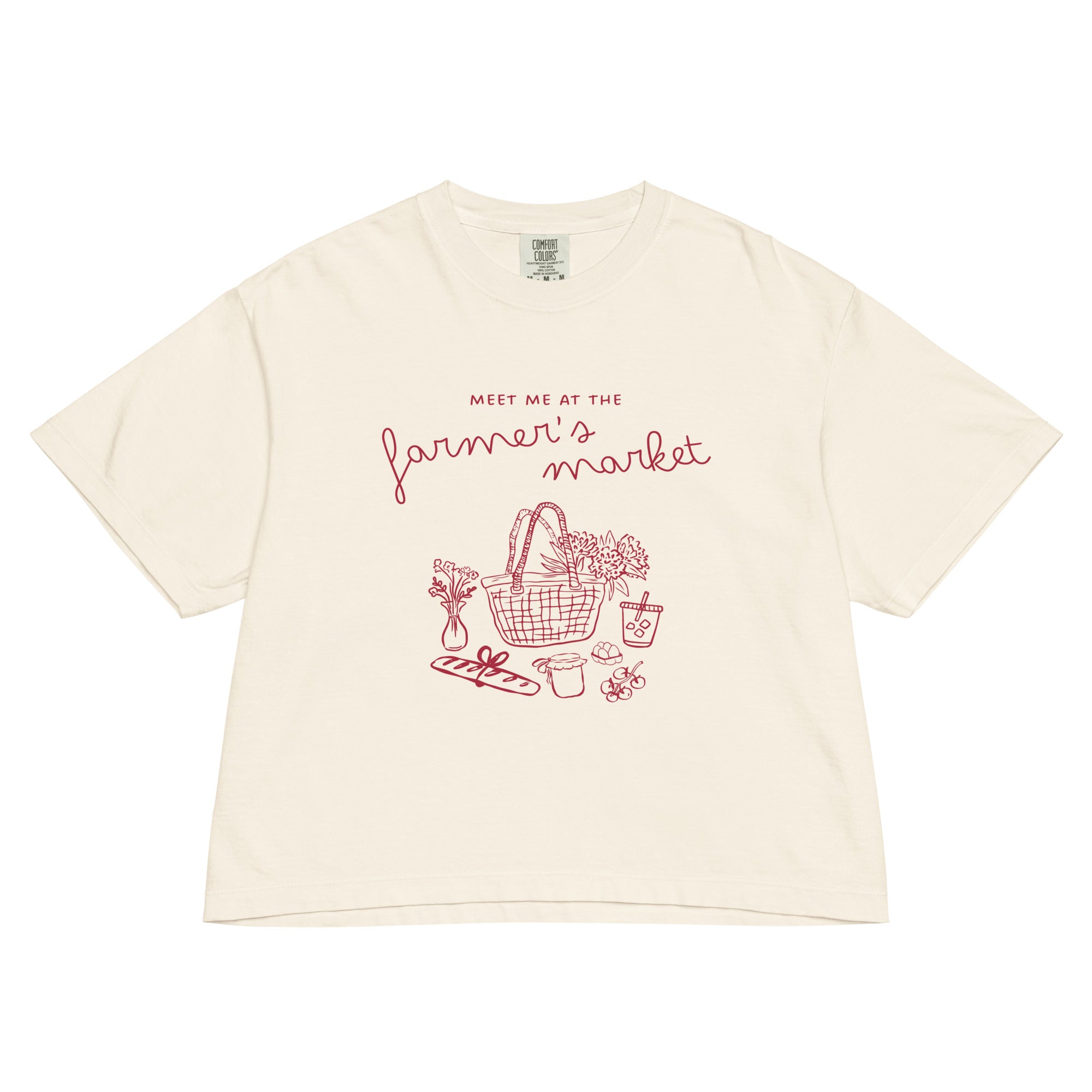 Beige t-shirt with red graphic and text 'meet me at the farmer's market' on a white background