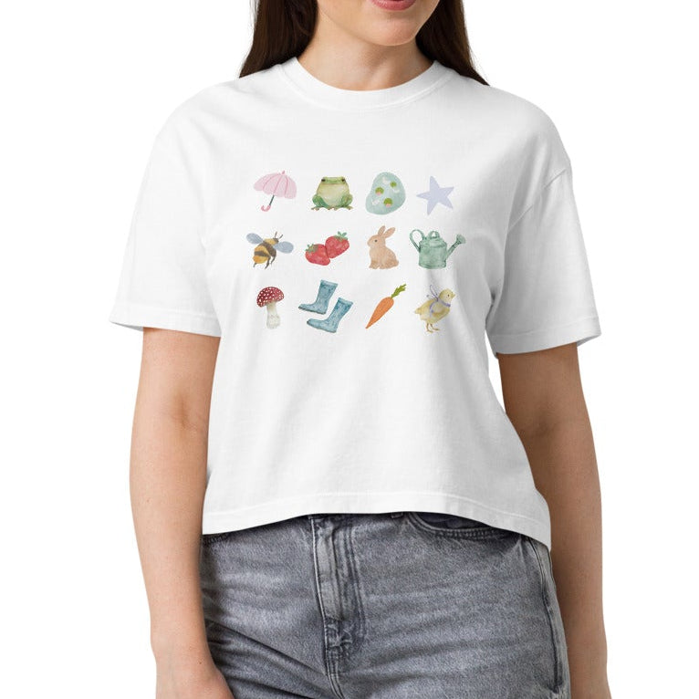 Woman wearing a white t-shirt with colorful graphics and gray jeans on a white background